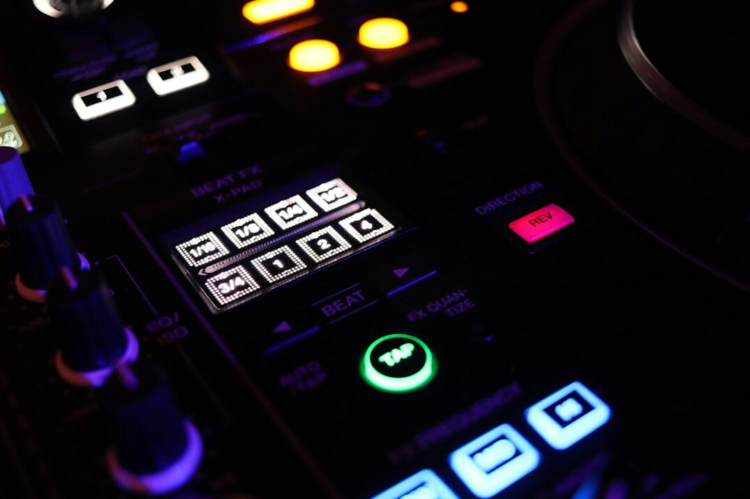Close-up of a vision mixer panel with lit buttons and faders